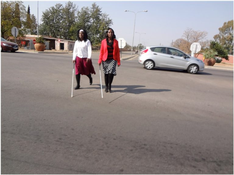 Two women with canes, crossing road as part of mobility training.