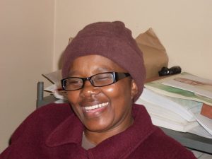 Blind SA employee, Victoria, sitting at her desk with a cheerful smile on her face.