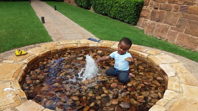 2-year old blind baby playing in the water of a fountain after he heard the sound 