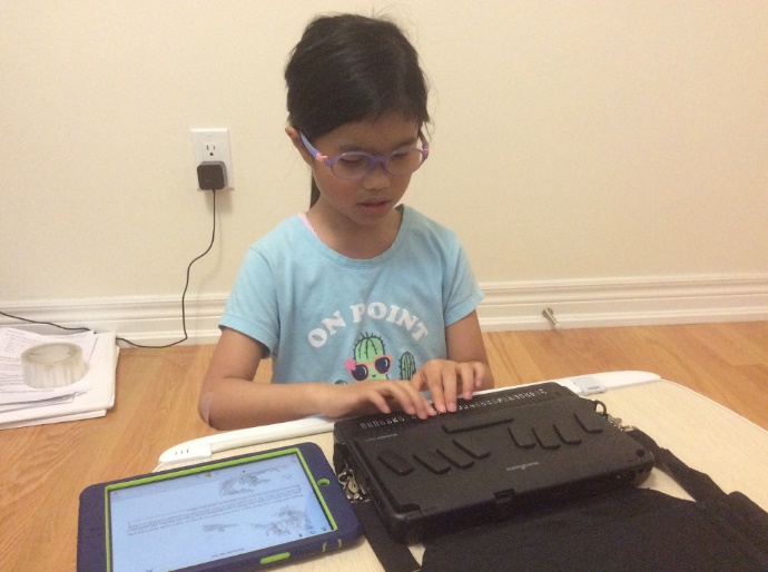 child using an ipad and braillenote touch to read