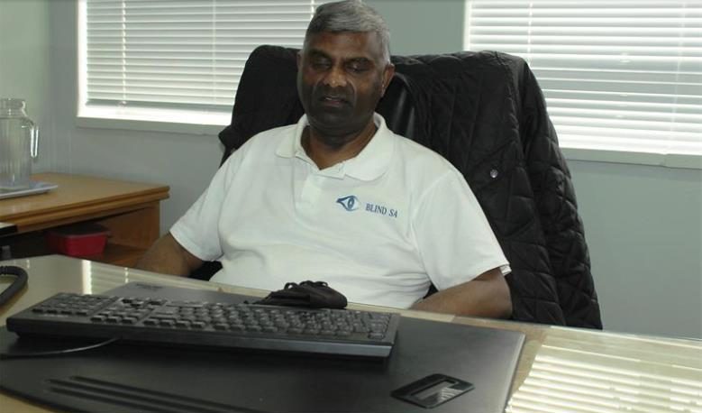 Jace, CEO of BlindSA sitting at his desk wearing a white golf shirt