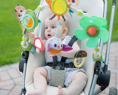 a baby in a stroller with toys of different shapes