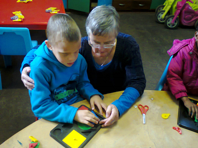 adult-showing-blind-boy-to-play-with-puzzle