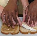 adult using the hand over hand method to teach a child to butter bread