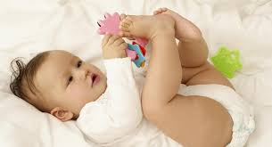 baby lying on her back playing with her hands and feet