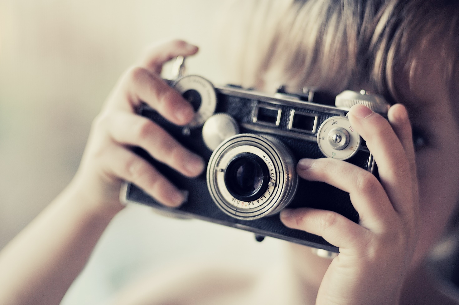 childs hands holding traditional camera to face