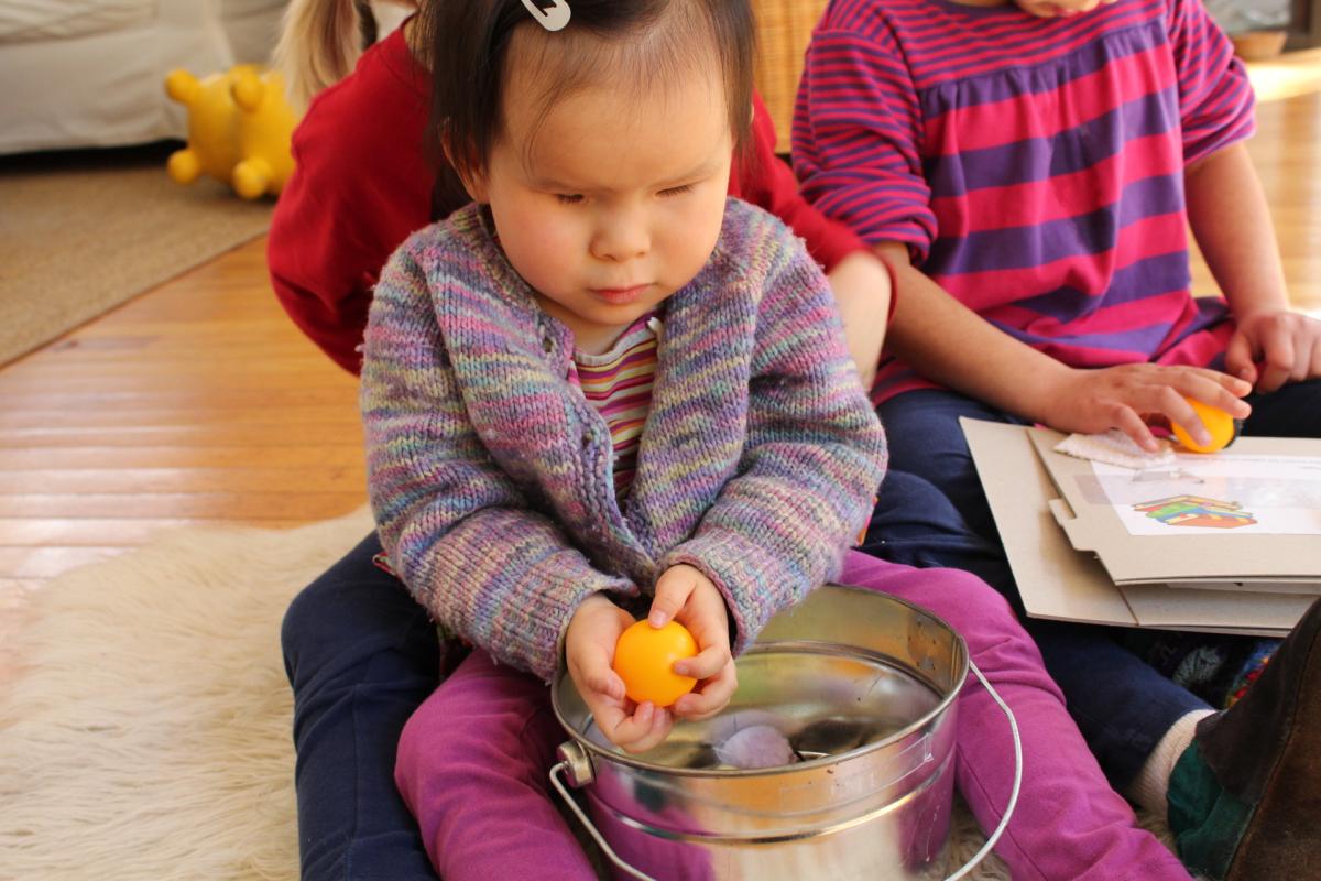 little girl playing with tactile objects in a bucket