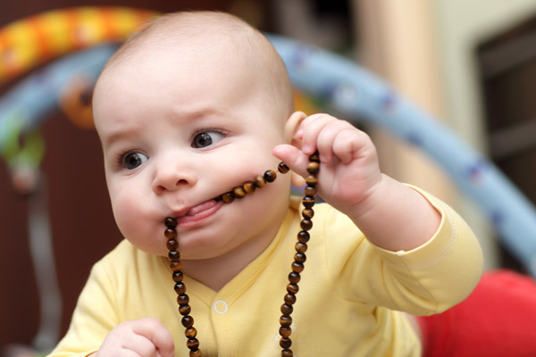 baby with a beaded necklace in their mouth